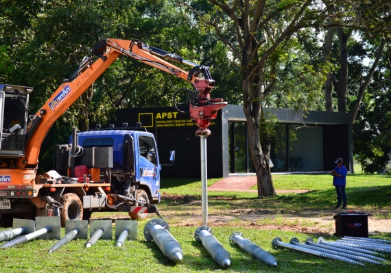 เข็มเหล็ก คือระบบฐานรากสมัยใหม่ที่ใช้เสาเข็มทำจากเหล็กกล้าแทนคอนกรีต มีลักษณะเป็นเสาเหล็กหน้าตัดกลมหรือแบบ H-Beam ที่สามารถตอกหรือติดตั้งลงดินได้โดยตรงเพื่อรองรับโครงสร้างด้านบน แนวคิดนี้ถือเป็นนวัตกรรมในประเทศไทยที่ช่วยให้งานติดตั้งฐานรากรวดเร็วขึ้น ไม่ต้องขุดหลุมขนาดใหญ่หรือรอคอนกรีตเซ็ตตัว โดยเสาเข็มเหล็กมักนิยมใช้ในพื้นที่ดินอ่อน พื้นที่ใกล้แหล่งน้ำ หรือในงานที่ต้องการความรวดเร็วในการติดตั้ง เช่น ฐานรากเสาไฟพลังงานแสงอาทิตย์ ป้ายขนาดใหญ่ หรือโครงสร้างเบาชั่วคราวต่าง ๆ เข็มเหล็กสามารถติดตั้งได้สะดวกในพื้นที่จำกัด ด้วยเครื่องจักรตอกหรือระบบเจาะสกรูลงดิน และสามารถถอดถอนเคลื่อนย้ายได้ง่ายเมื่อหมดอายุการใช้งาน   ข้อดี: เข็มเหล็กโดดเด่นเรื่องความรวดเร็วในการทำงาน – สามารถติดตั้งฐานรากแล้วดำเนินการขึ้นโครงสร้างต่อได้ทันทีโดยไม่ต้องรอให้คอนกรีตแข็งตัว นอกจากนี้ยังรองรับน้ำหนักได้ดีในชั้นดินอ่อนหรือพื้นที่ใกล้น้ำ เนื่องจากเสาเหล็กมีความยืดหยุ่นและแรงต้านทานต่อการโก่งตัวสูง อีกทั้งงานติดตั้งค่อนข้างสะอาดและลดขั้นตอนหลายอย่างเมื่อเทียบกับการทำฐานรากคอนกรีต (ไม่ต้องเทปูนหรือทำแบบหล่อหน้างาน)   ข้อจำกัด: เนื่องจากวัสดุเป็นเหล็ก การกัดกร่อนจึงเป็นปัจจัยสำคัญที่ต้องคำนึงถึง หากติดตั้งเข็มเหล็กในดินที่มีความชื้นสูงหรือดินเค็ม ต้องมีการป้องกันสนิมที่ดี (เช่น การชุบกัลวาไนซ์หรือทาสีเคลือบป้องกัน) เพื่อยืดอายุการใช้งานของฐานรากเหล็ก นอกจากนี้ราคาเข็มเหล็กอาจสูงกว่าระบบเสาเข็มคอนกรีตขึ้นอยู่กับขนาดและประเภทของเหล็กที่ใช้ แต่เมื่อพิจารณาประหยัดเวลาการติดตั้งและความสะดวก เข็มเหล็กก็เป็นทางเลือกที่คุ้มค่าในหลายกรณี   ซึ่งได้รับการยอมรับอย่างแพร่หลายในงานติดตั้งฐานรากยุคใหม่ ถือเป็นการต่อยอดนวัตกรรมฐานรากที่ตอบโจทย์งานโครงสร้างเบาและงานติดตั้งเสาไฟฟ้ากลางแจ้งในประเทศไทย